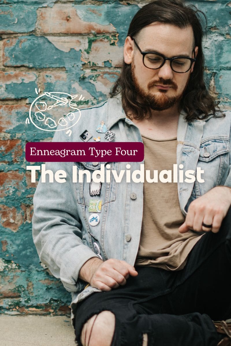 Photo of a young man with long hair and glasses sitting against a distressed brick wall, wearing a denim jacket with pins and black ripped jeans. Overlaid text reads “Enneagram Type Four – The Individualist.”