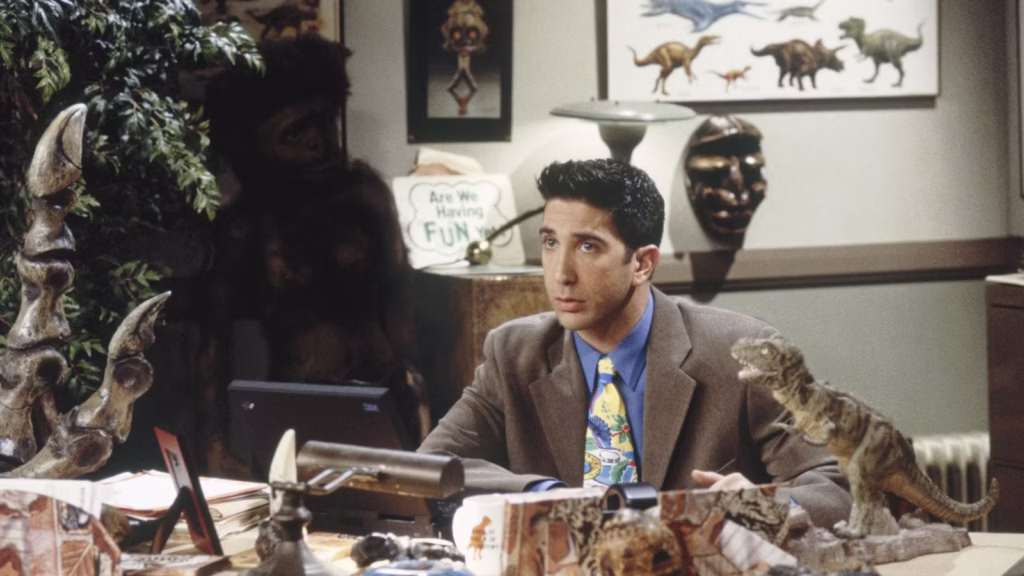Photo of Ross Geller from the TV show "Friends" in his office surrounded by dinosaur memorabilia 