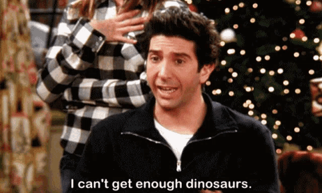 Animated GIF of Ross Geller smiling excitedly and saying, "I can't get enough dinosaurs," with the subtitle displayed on screen.
